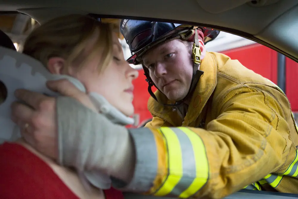 Picture of a firefighter putting a neck brace on a woman who was just in a truck and car accident.